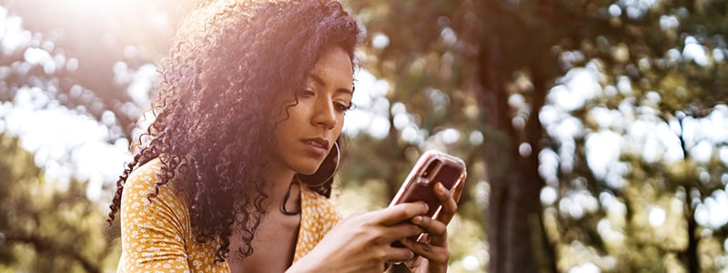 A woman on her phone reading about how to remove GPS and other metadata locations from photos.