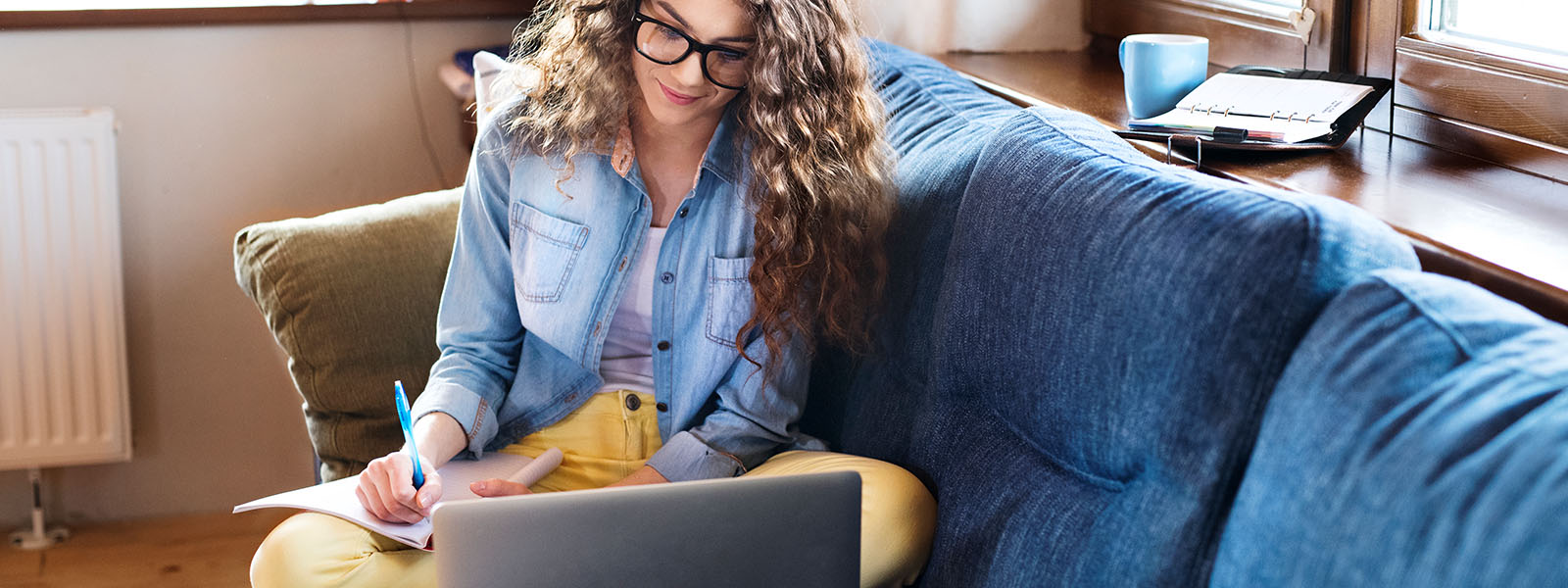 A woman taking notes on how to free up RAM while looking at a laptop.