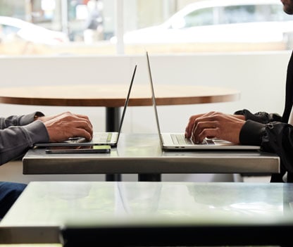 Two laptops sitting back-to-back, illustrating how fileless malware can spread quickly and easily between devices.