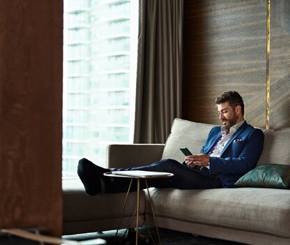 A man in a business suit looks concerned as his phone is taken over by criminals, illustrating the dangers of phone hijacking.