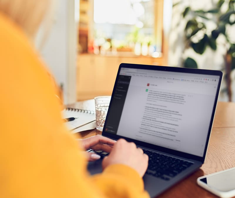 A focused woman is intensively typing on her laptop.