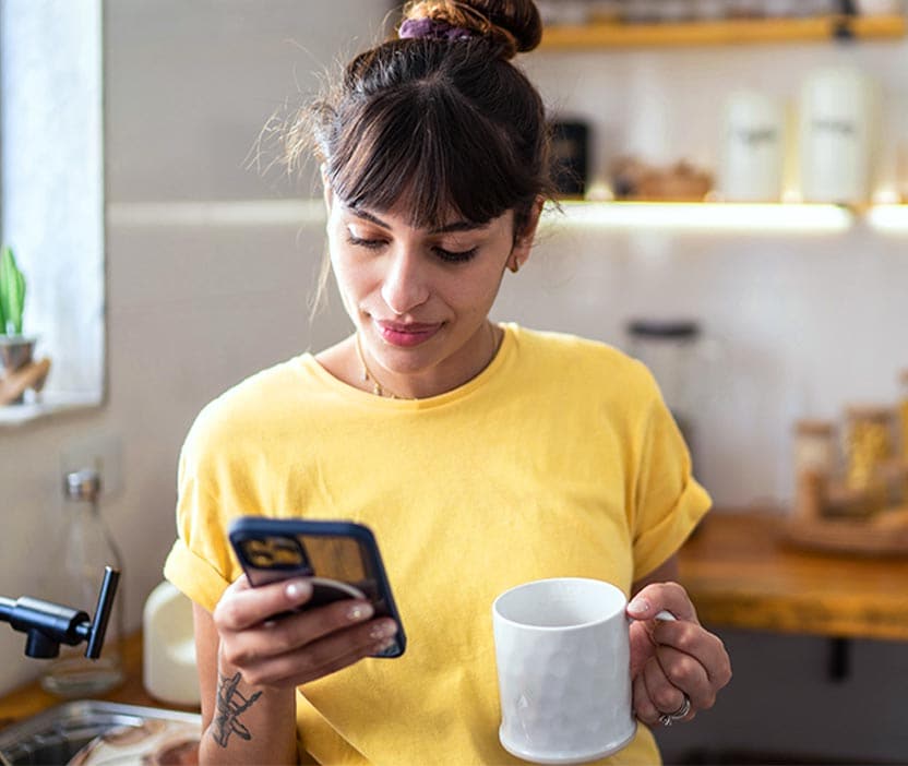 A woman holding a smartphone, looking concerned, wondering if her phone is listening to her.