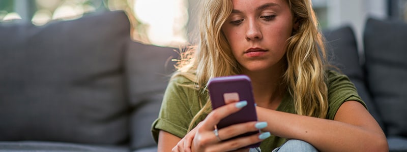 A woman researching on her phone about how to identify and protect herself from bot attacks.