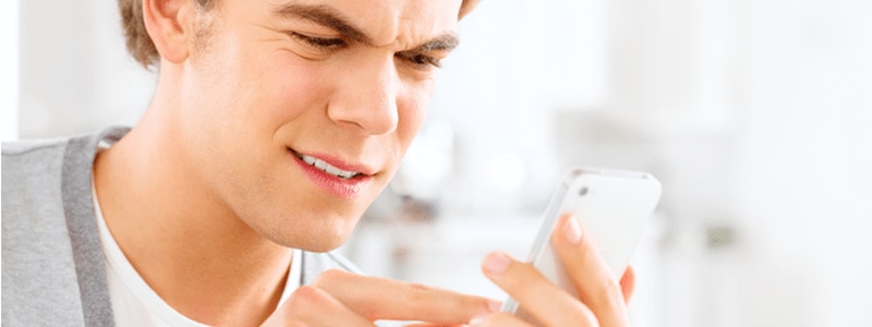 A person looking at their phone in confusion, trying to decipher the meaning of a strange text message with random letters and numbers.