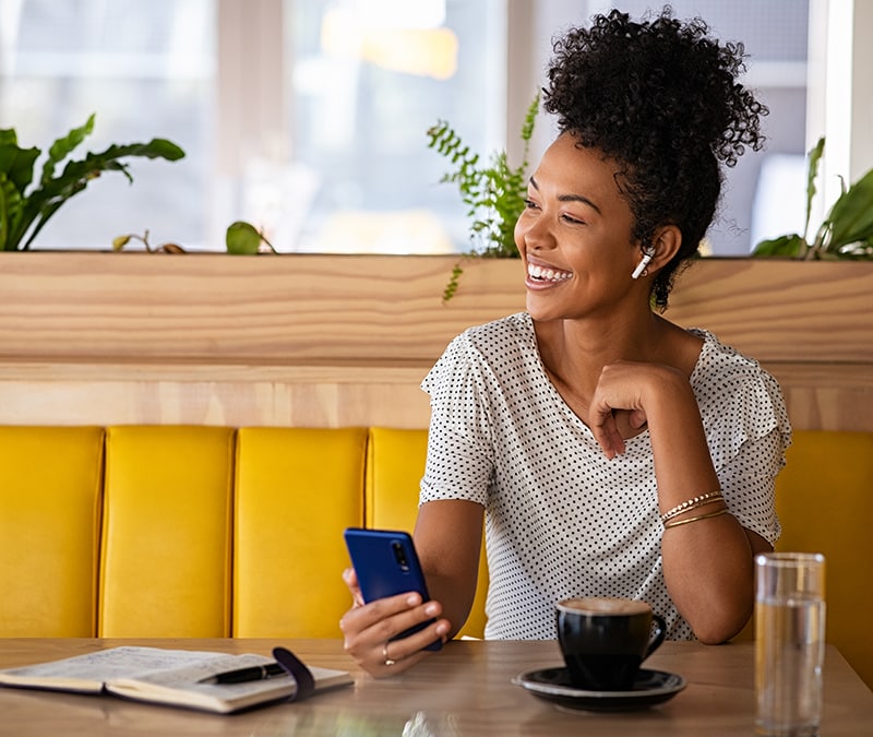 A woman engrossed in her phone while sitting in a cafe, enjoying her time in a cozy and relaxed environment.