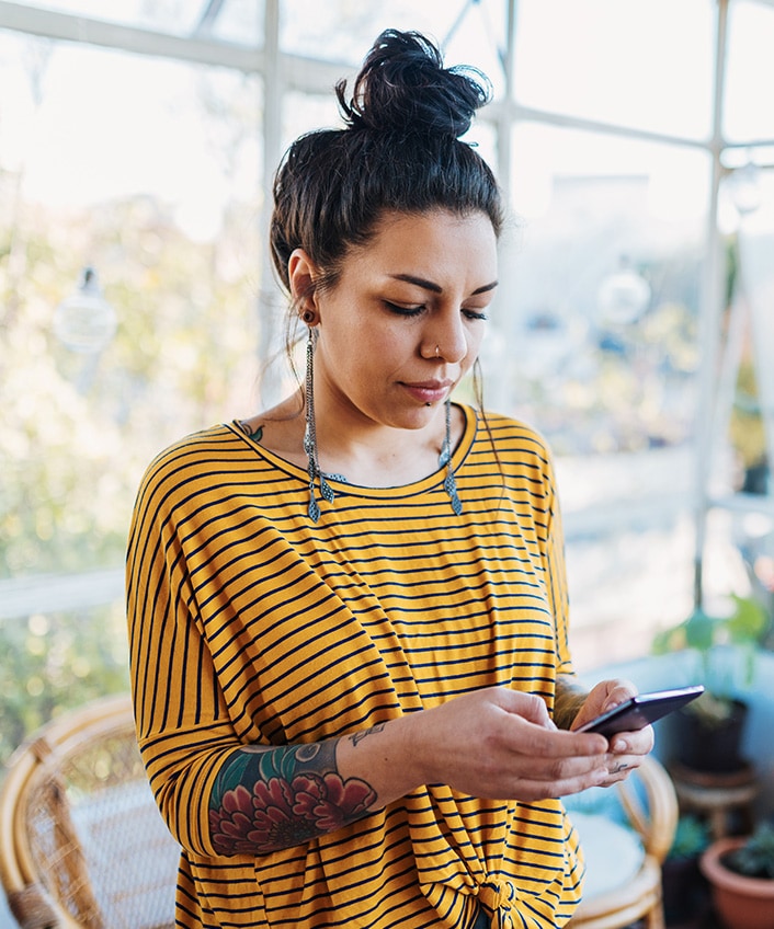 A woman uses her smartphone to answer the question, “What is a chatbot?