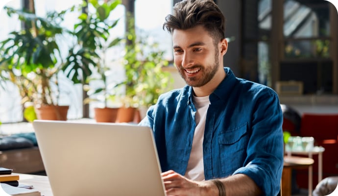 Man smiling using laptop launching Norton Safe Search.
