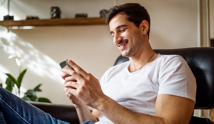 Man sitting and smiling at a phone