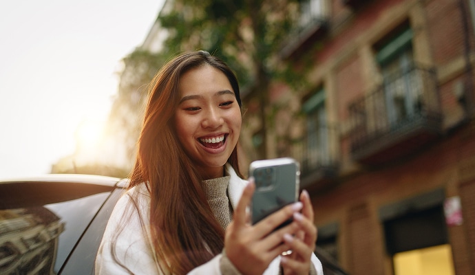 Woman in the street, smiling at her phone